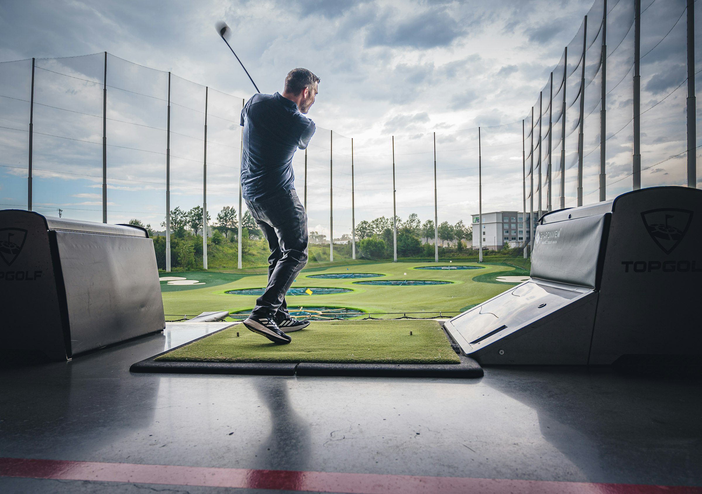 Golfer practising his swing in a driving-range bay